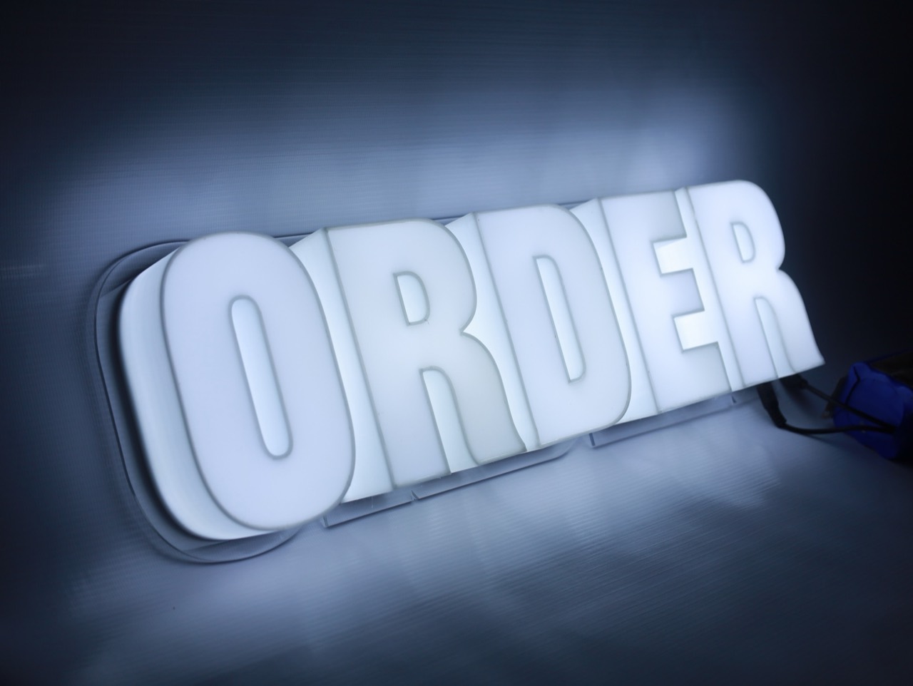 ป้ายไฟคำว่า ORDER สีขาววางบนพื้นหลังเรียบ