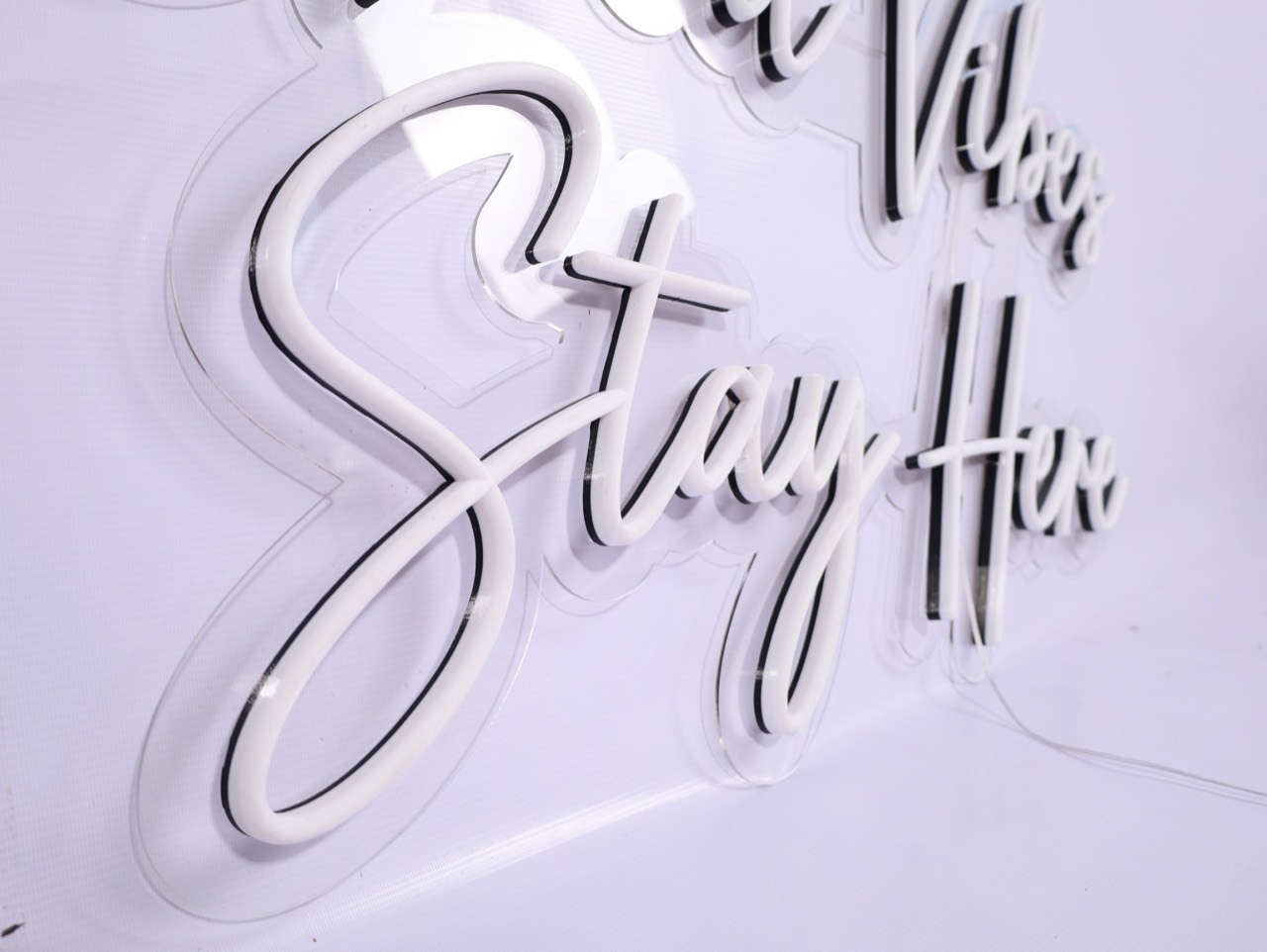 ป้ายตัวเขียนสไตล์นีออนคำว่า Stay High บนฐานสีขาว
