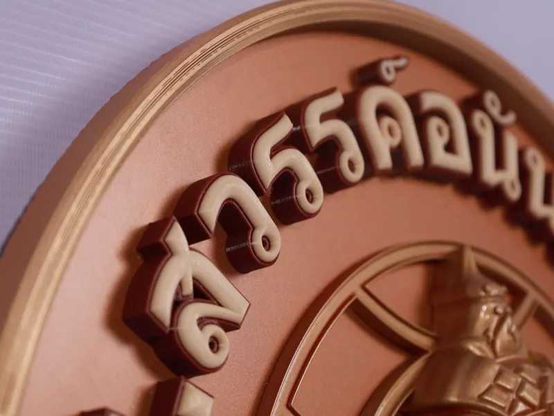 ตัวอักษรไทยนูนสีครีมบนแผ่นวงกลมสีชมพูน้ำตาล